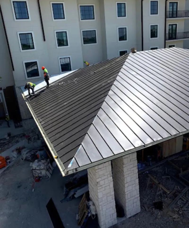 Crew installing standing seam metal roof panels on a commercial project in Fort Worth